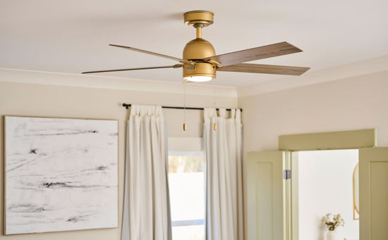 Erling Ceiling Fan in luxe gold finish mounted with downrod on white ceiling.