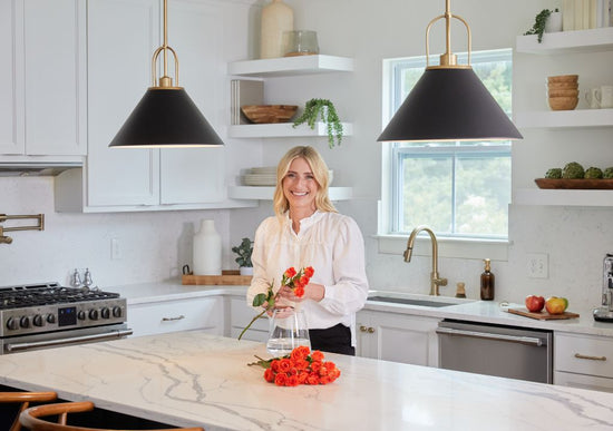 Jasmine Roth in kitchen cutting flowers on an island lit by two Carrington Isle pendants.