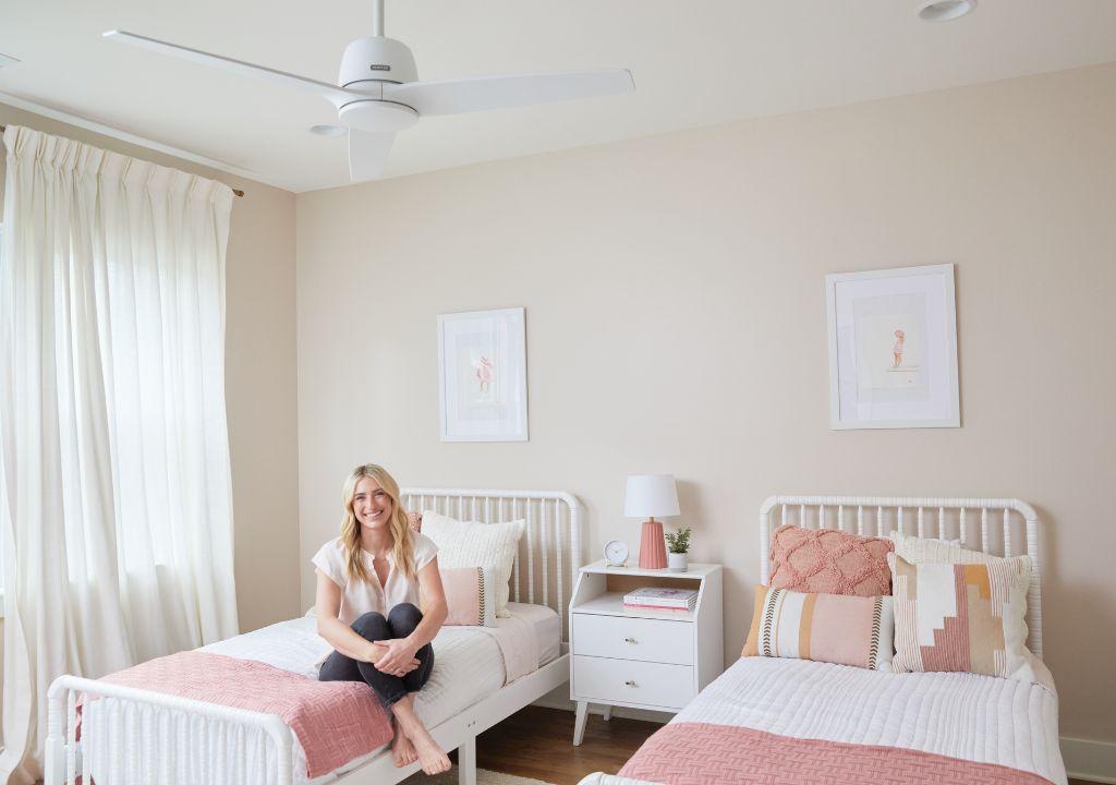 Jasmine Roth sitting on a bed under the Malden ceiling fan.