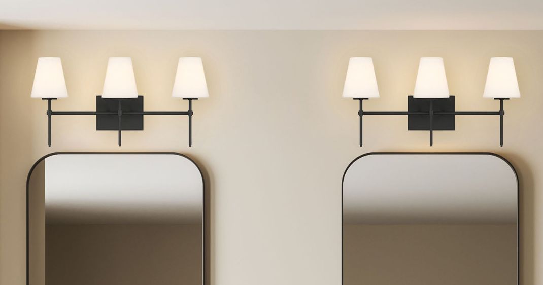 Interior lighting image featuring two black three-light vanity fixtures with white shades installed above coordinating rounded rectangular mirrors.
