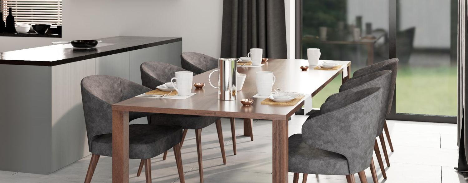 Modern dining area with a wooden table set for a meal, surrounded by upholstered chairs, adjacent to a kitchen island and large glass doors letting in natural light