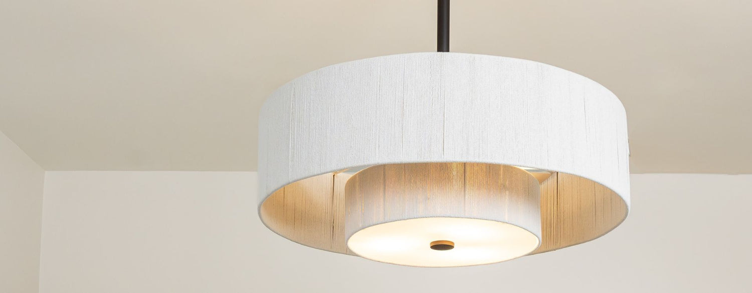 Hero angle of drum-style ceiling fan highlighting layered shade, warm glow, and overall form