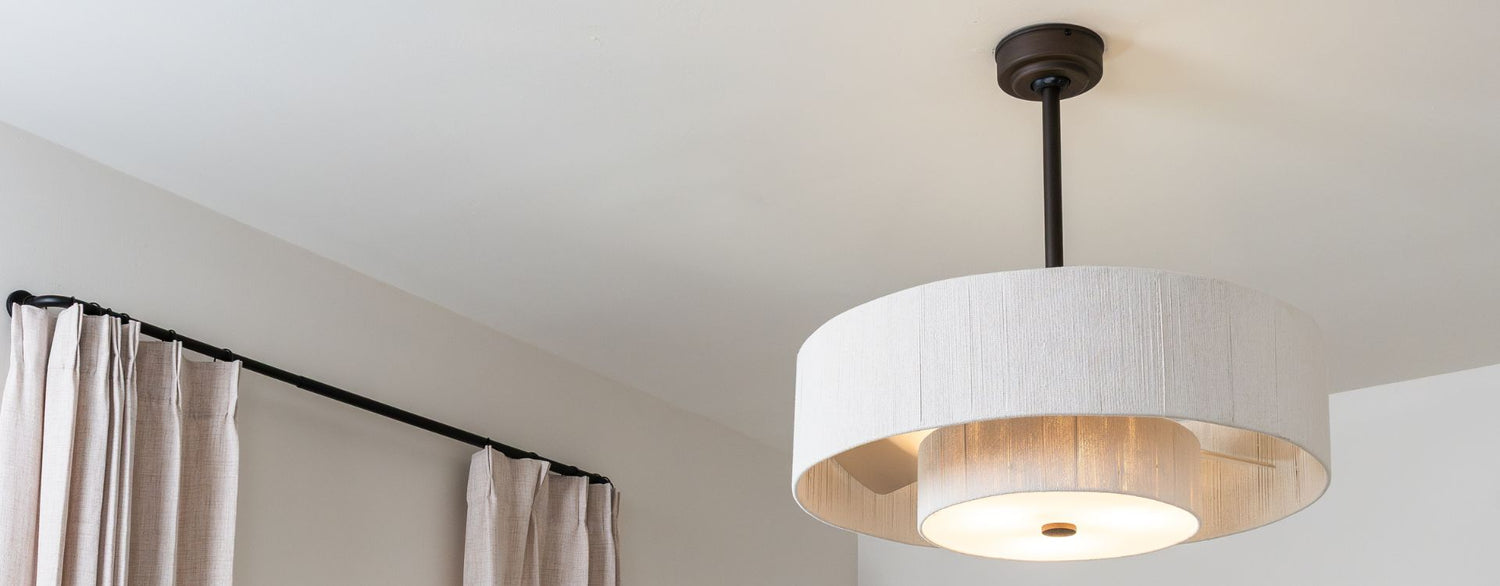 Close-up of a contemporary drum pendant light with a textured fabric shade and warm diffused glow.